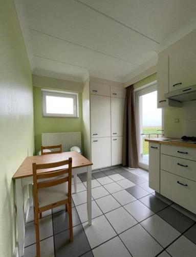 a kitchen with a table and chairs and a window at Het Damhert in Kortenaken