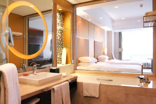 a bathroom with a sink and a bed in a mirror at Crowne Plaza Yantai Sea View by IHG in Yantai