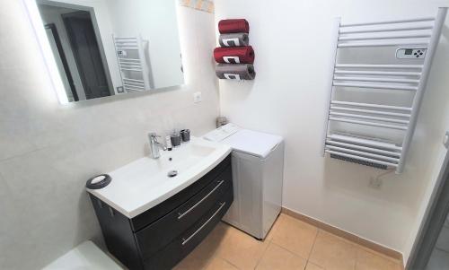 ein weißes Badezimmer mit einem Waschbecken und einem Spiegel in der Unterkunft L'Atalante, 2 pièces 47m2 rénové résidence piscine in Villeneuve-Loubet