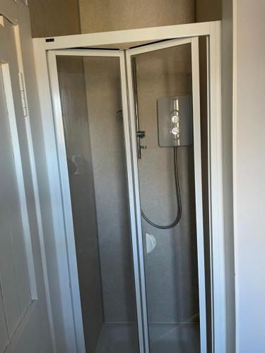 a shower with a glass door in a bathroom at Newsagents Flat in Lairg