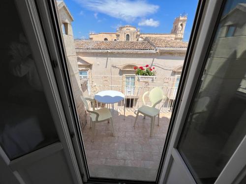 Blick aus einem Fenster auf eine Terrasse mit einem Tisch und Stühlen in der Unterkunft Plaza Rooms in Avola