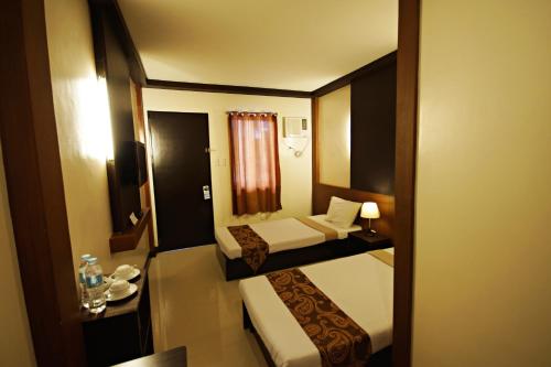 a small room with two beds and a window at Pacific Palm Suites Davao powered by Cocotel in Davao City