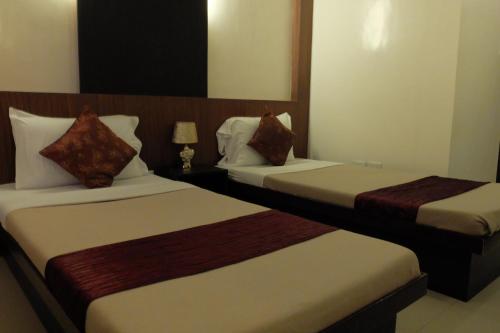 a hotel room with two beds and a lamp at Pacific Palm Suites Davao powered by Cocotel in Davao City