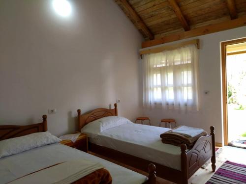 1 dormitorio con 2 camas y ventana en Bujtina Peshtan Guesthouse&Camping, en Tepelenë
