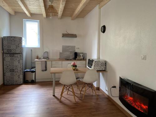 une cuisine avec une table et deux chaises ainsi qu'une cheminée dans l'établissement Le Chêne: Petit Chalet cosy proche de Mulhouse, à Riedisheim