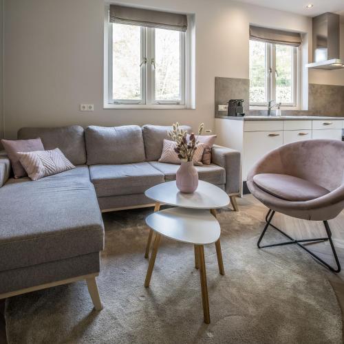 a living room with a couch and a table at Vakantiehuis in een prachtige bosrijke omgeving in Twente! in Bornerbroek