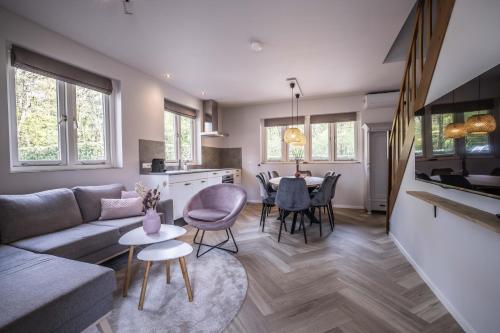 a living room with a couch and a table at Vakantiehuis in een prachtige bosrijke omgeving in Twente! in Bornerbroek