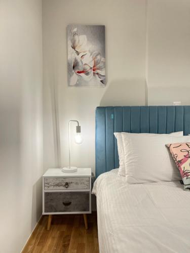 a bedroom with a bed with a blue headboard and a night stand at Athenean Modern Escape near Marina Flisvos in Athens