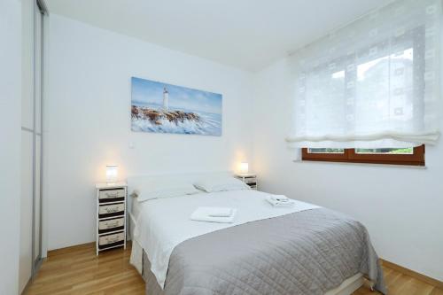 a white bedroom with a bed and a window at Apartment and room Mare in Zadar