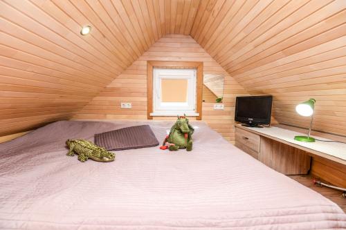 uma cama grande num quarto de madeira com dois bichos de peluche em INKARAS Aparthotel em Palanga
