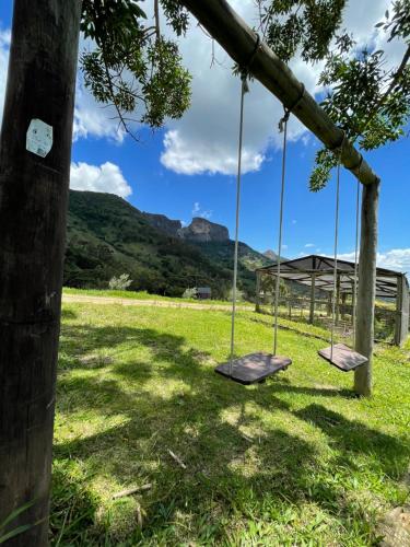 two swings in a field with mountains in the background at Rancho do Paioleiro - Suites in São Bento do Sapucaí