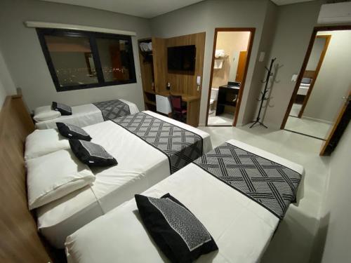a hotel room with three beds and a mirror at VIPPER Hotel in Aparecida