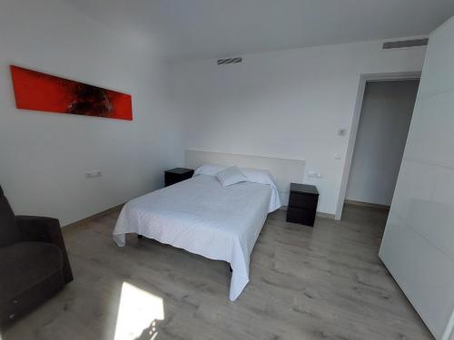 - une chambre avec un lit blanc et une peinture rouge sur le mur dans l'établissement Àtic al centre de Girona, à Gérone