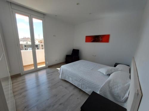 une chambre blanche avec un lit et une grande fenêtre dans l'établissement Àtic al centre de Girona, à Gérone