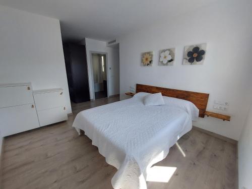 1 dormitorio con cama blanca y suelo de madera en Àtic al centre de Girona, en Girona