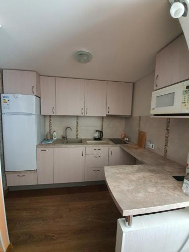 a kitchen with white cabinets and a white refrigerator at Vidumgrāvja apartamenti in Ventspils