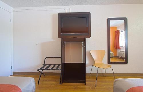a tv on a stand in a room with a mirror at Motel 6-East Brunswick, NJ in East Brunswick