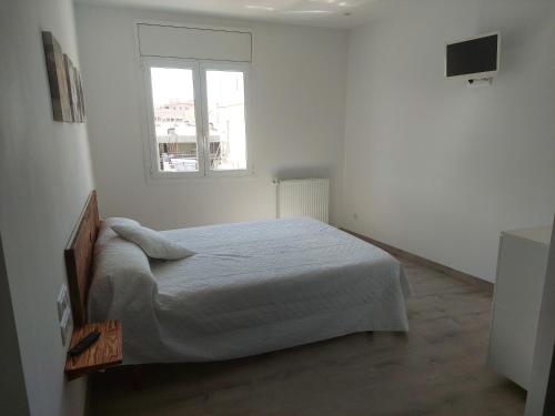 a white bedroom with a bed and a window at Àtic al centre de Girona in Girona