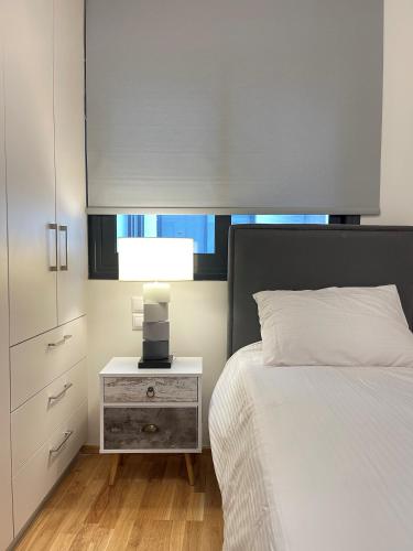 a bedroom with a bed and a night stand with a lamp at Athenean Modern Escape near Marina Flisvos in Athens