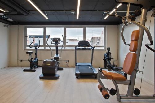 a gym with cardio equipment in a room with a window at Aparthotel Bcn Montjuic in Barcelona