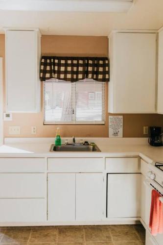 a kitchen with white cabinets and a sink and a window at The Long Barn Lodge in Long Barn