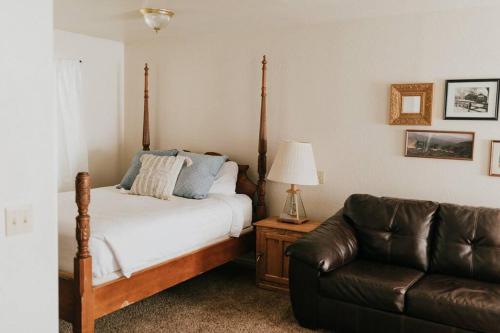 a bedroom with a bed and a leather couch at The Long Barn Lodge in Long Barn