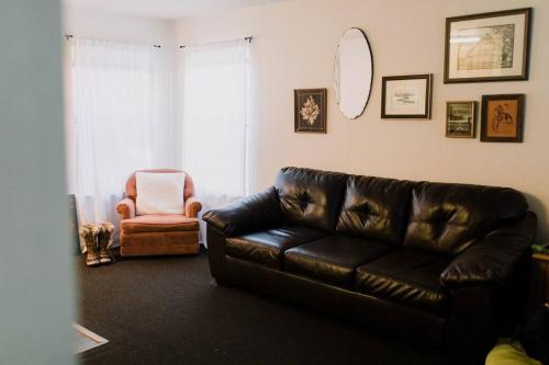 a living room with a leather couch and a chair at The Long Barn Lodge in Long Barn