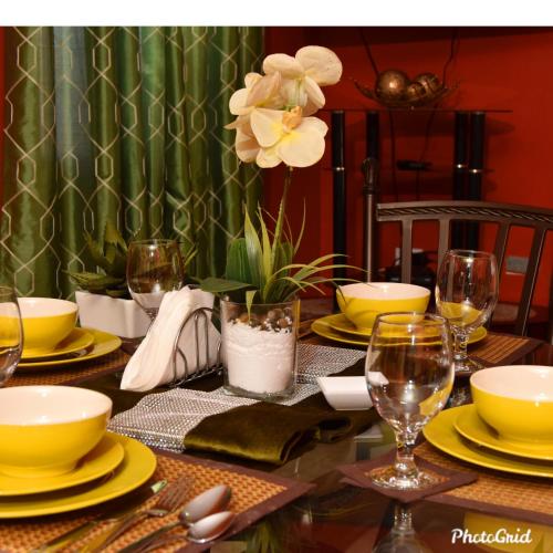a dining room table with yellow plates and glasses at Caribbean estate deluxe 2 in Portmore