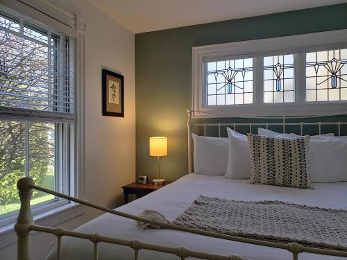 a bedroom with a bed with two windows at Sand Bar Cottage Inn in Bar Harbor