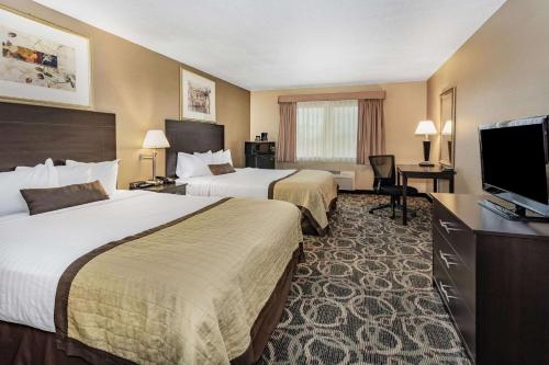 a hotel room with two beds and a flat screen tv at Baymont by Wyndham Casper East in Evansville
