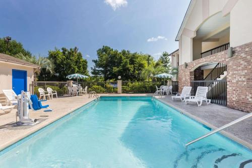 una piscina con sillas y mesas y un edificio en Howard Johnson by Wyndham Savannah GA en Savannah