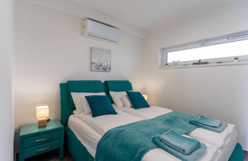 a bedroom with a green and white bed with a window at Relax Beach Apartman in Fonyód