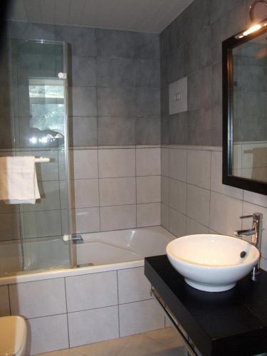 a bathroom with a sink and a shower and a tub at The Originals City Hotel de l Ange Guebwiller in Guebwiller