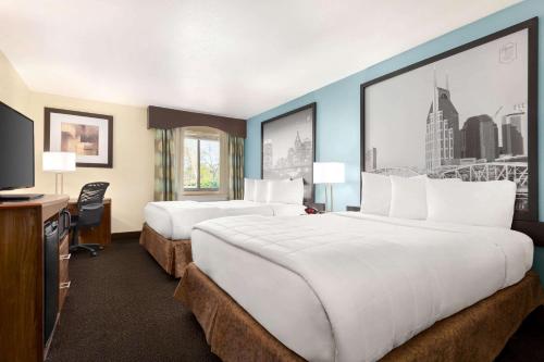 a hotel room with two beds and a television at Luxe Studios Nashville Airport in Nashville