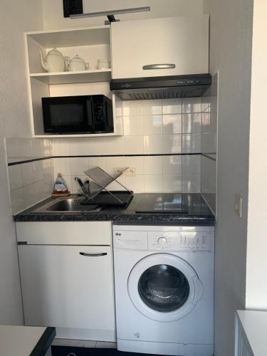 une cuisine avec un lave-linge et un micro-ondes dans l'établissement Studio confort port de Frejus, à Fréjus