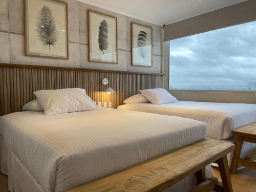 a bedroom with two beds and a large window at Apart Hotel Las Terrazas Suite in Chillán