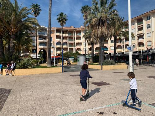 une femme et un enfant voyageant en scooter devant un bâtiment dans l'établissement Studio confort port de Frejus, à Fréjus