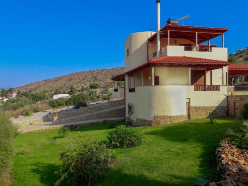 Direti villa في Kalamitsi Amygdali: مبنى به ساحة خضراء بجوار تل