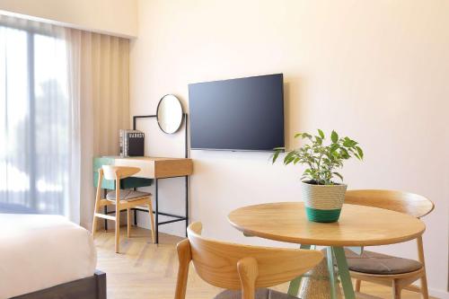 a room with a table and a tv on a wall at Hyatt House Johannesburg, Sandton in Johannesburg