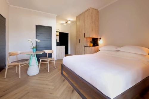 a bedroom with a large white bed and a table at Hyatt House Johannesburg, Sandton in Johannesburg