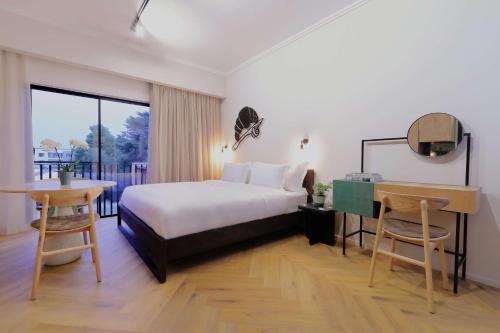 a hotel room with a bed and a desk and a table at Hyatt House Johannesburg, Sandton in Johannesburg