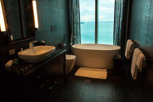 a bathroom with a tub and a sink and a toilet at Grand Papua Hotel, a member of Radisson Individuals in Port Moresby