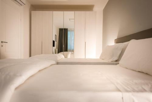 a white bedroom with two beds and a mirror at TURINHOMETOWN Residence Apartments in Turin