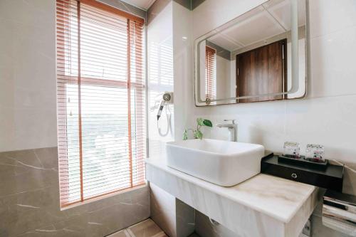een witte badkamer met een wastafel en een spiegel bij Golden Coto Hotel in Dao Co To