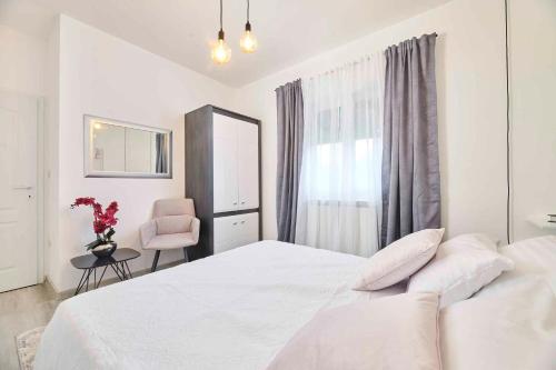 a white bedroom with a white bed and a pink chair at Holiday home in Murine - Istrien 42601 in Murine