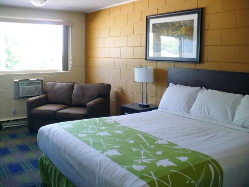 a hotel room with a bed and a chair at Westgate Inn in Portage La Prairie