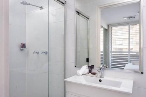 a white bathroom with a sink and a shower at Heart Of Manly and Close to Everything in Sydney