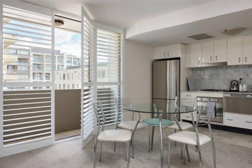 eine Küche mit einem Glastisch und Stühlen im Zimmer in der Unterkunft Heart Of Manly and Close to Everything in Sydney