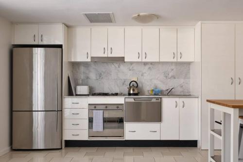 eine Küche mit weißen Schränken und einem Kühlschrank aus Edelstahl in der Unterkunft Heart Of Manly and Close to Everything in Sydney