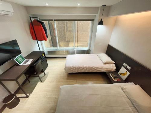 a bedroom with two beds and a desk and a window at Formosa 101 Taipei Main Branch in Taipei
